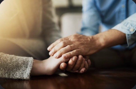 Two people holding hands in a gesture of care and connection